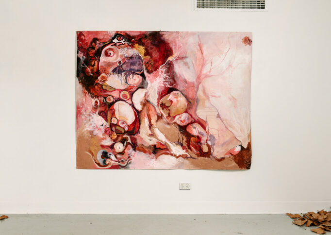 A large unframed abstract painting in reds, pinks, beige and rose colours.