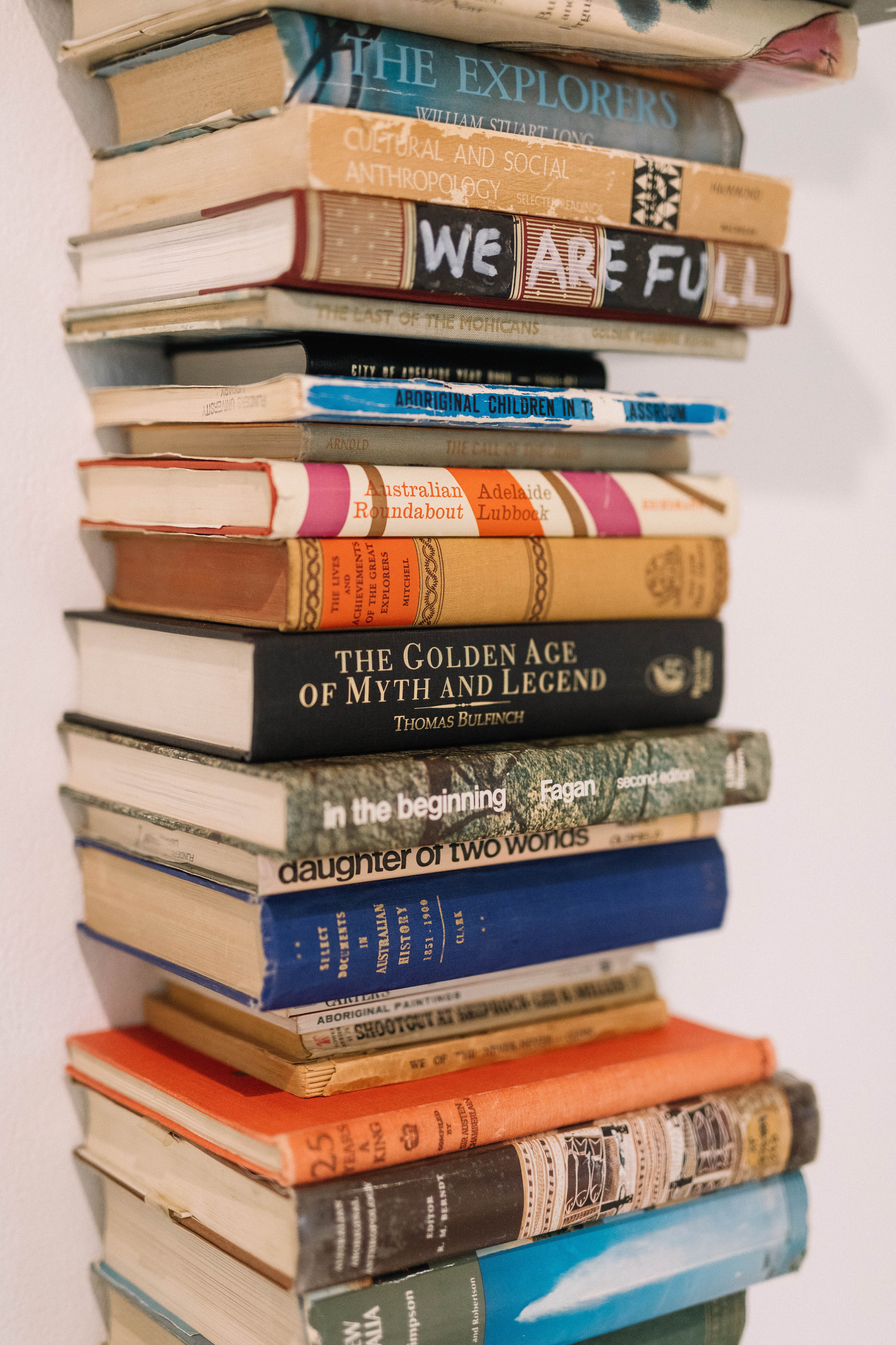 Detail of a sculpture of a tall stack of books, spines facing us with various titles.