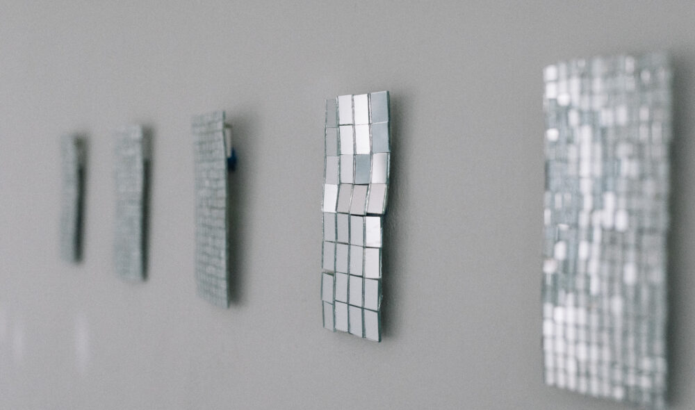 A detailed photograph of mirrored artworks installed on a wall