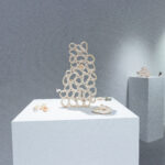 A photograph inside an art gallery of small ceramic sculptures on plinths