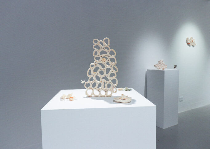 A photograph inside an art gallery of small ceramic sculptures on plinths